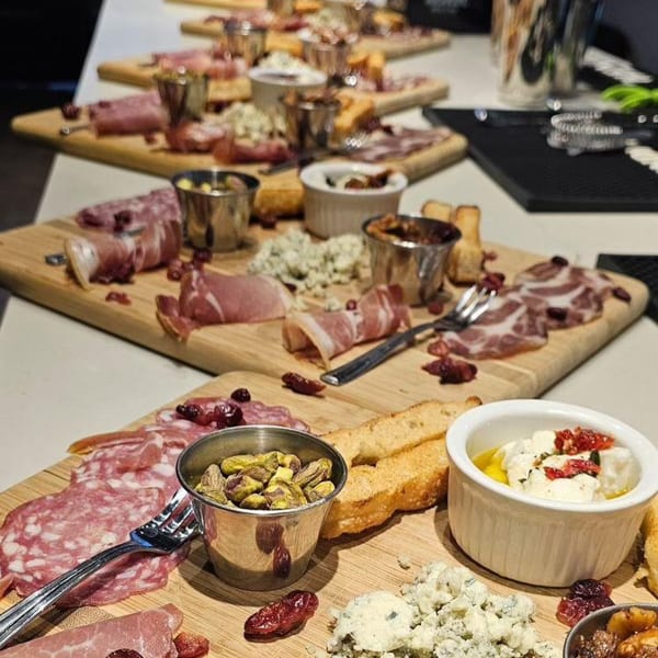Multiple wooden boards laden with Italian charcuterie, cheeses, nuts, and bread slices.